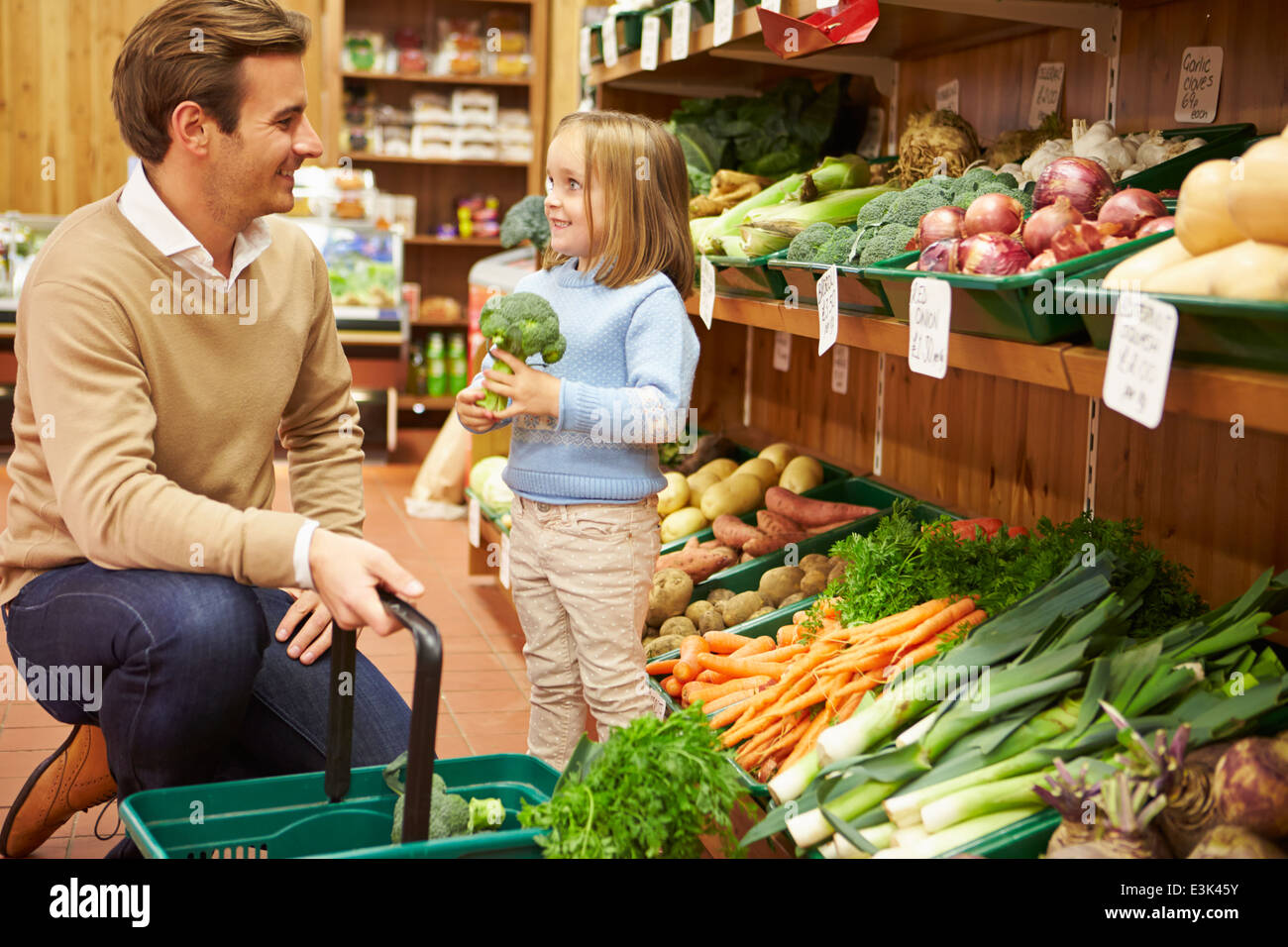 Father And Daughter Choosing Fresh Vegetables In Farm Shop Stock Photo