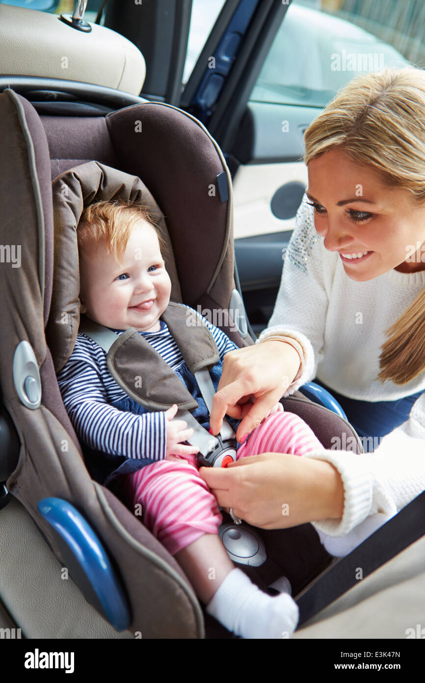 Mother Putting Baby Into Car Seat Stock Photo