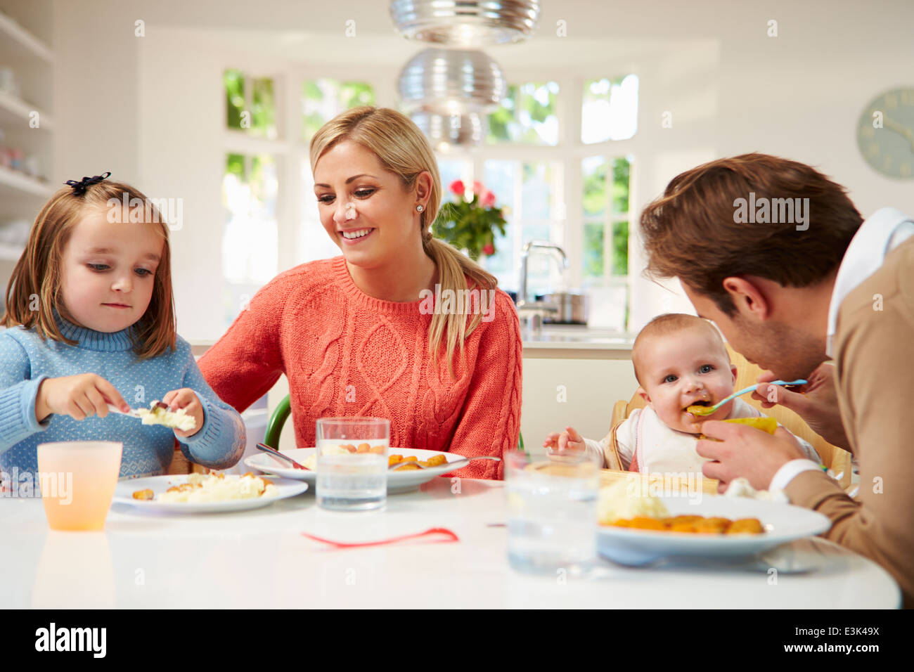 Family With Young Baby Eating Meal At Home Stock Photo