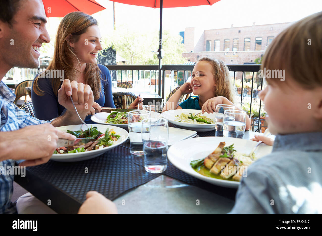 Family Enjoying Meal At Outdoor Restaurant Stock Photo