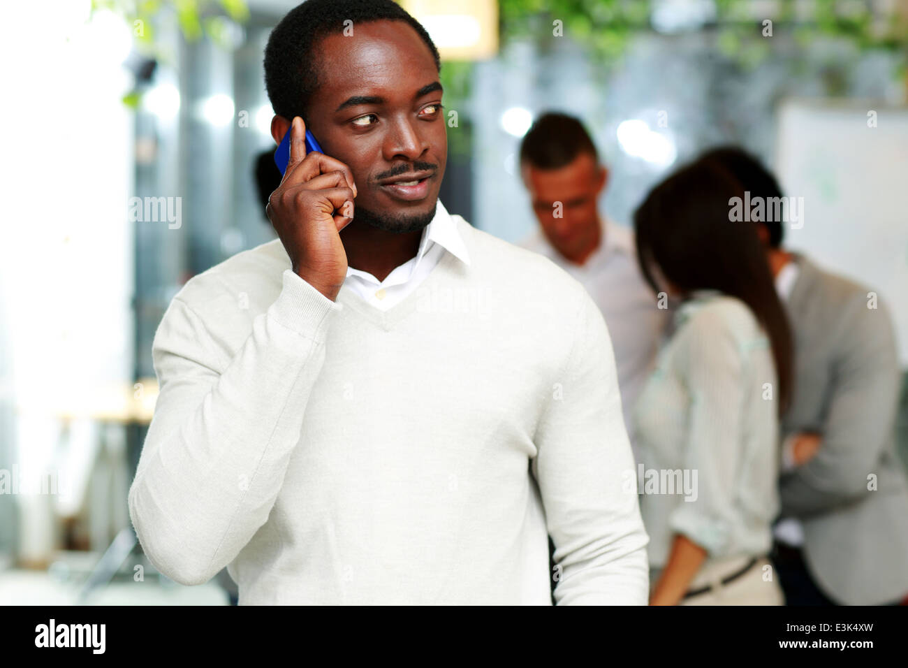 Handsome african businessman talking on the smartphone in front of colleagues Stock Photo