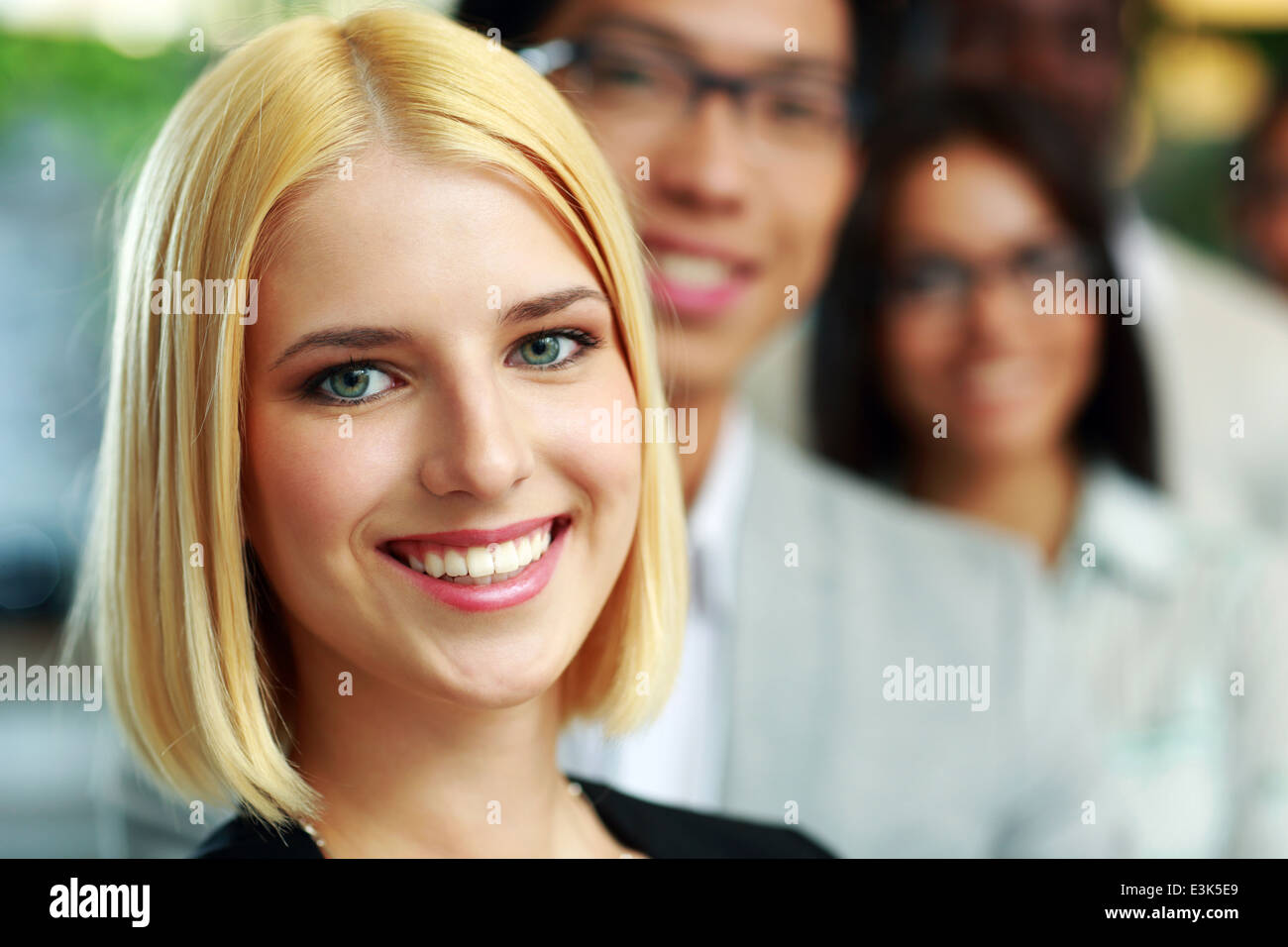 Portrait of a happy businesswoman standing in front of colleagues Stock Photo
