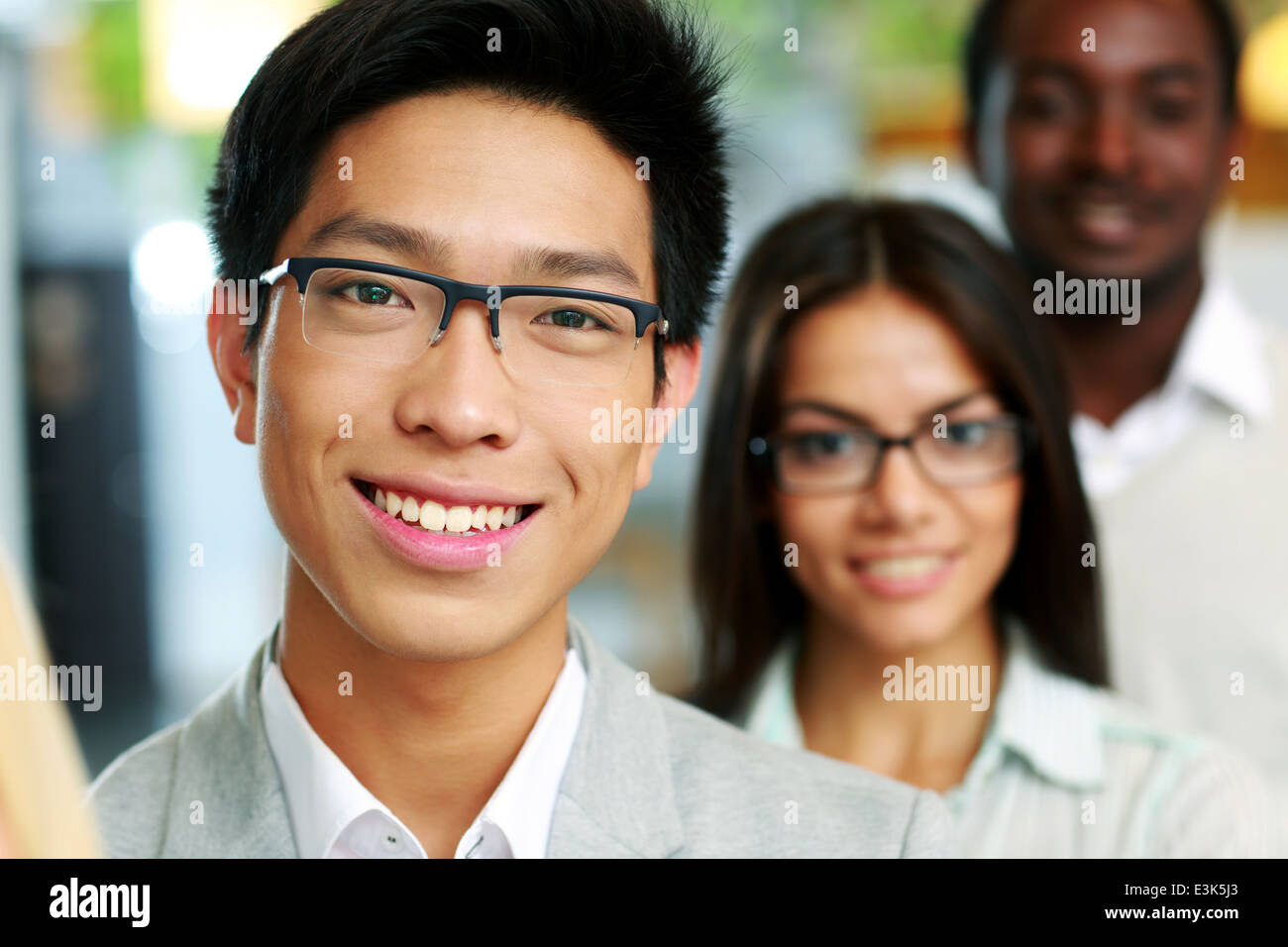 Portrait of a smiling asian businessman standing in front of colleagues  Stock Photo