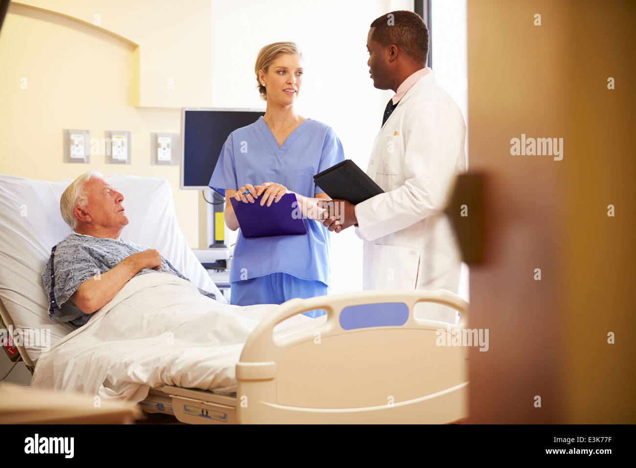 Medical Team Meeting With Senior Man In Hospital Room Stock Photo