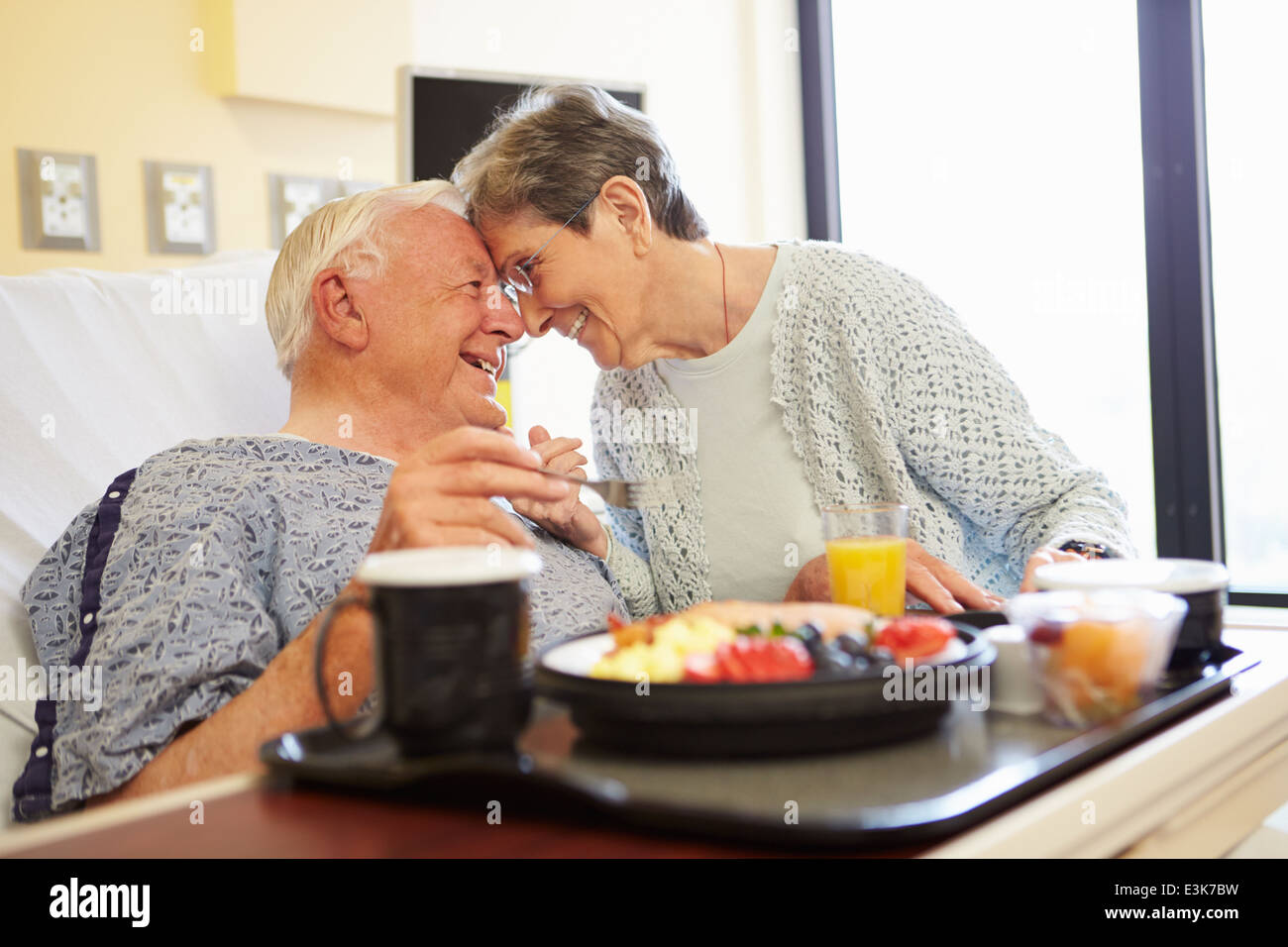 Senior Couple In Hospital Room As Male Patient Has Lunch Stock Photo