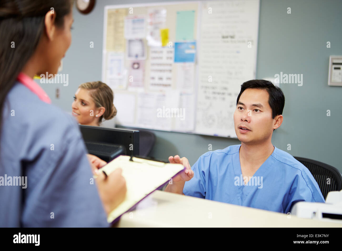 Male And Female Nurse In Discussion At Nurses Station Stock Photo