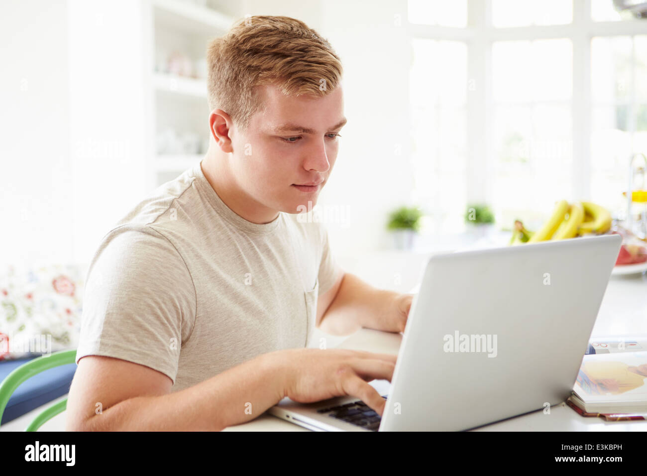 Teenage Boy Studying On Laptop At Home Stock Photo