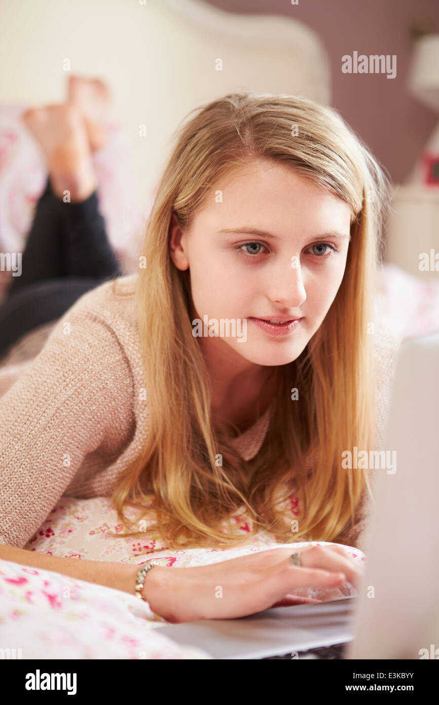 Teenage Girl Lying On Bed Using Laptop Stock Photo Alamy