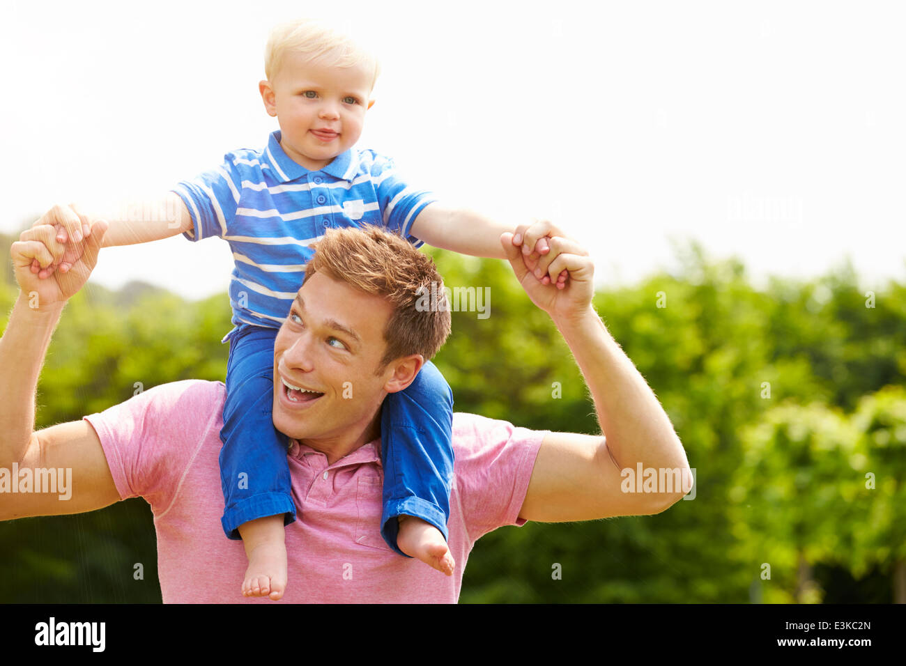Father Giving Young Son Ride On His Shoulders In Garden Stock Photo