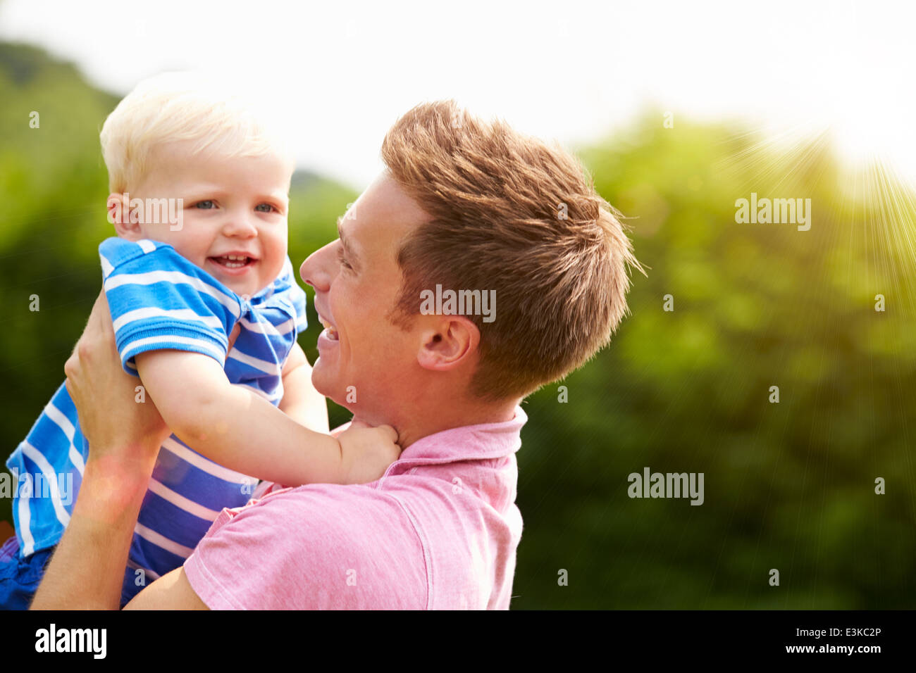 Father Hugging Young Son In Garden Stock Photo
