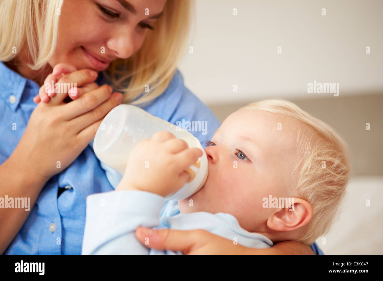Mother Giving Baby Son Bottle Of Milk Stock Photo