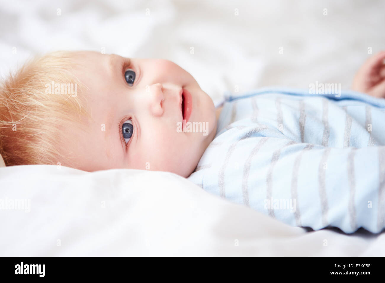 Young Baby Boy Lying In Bed Stock Photo