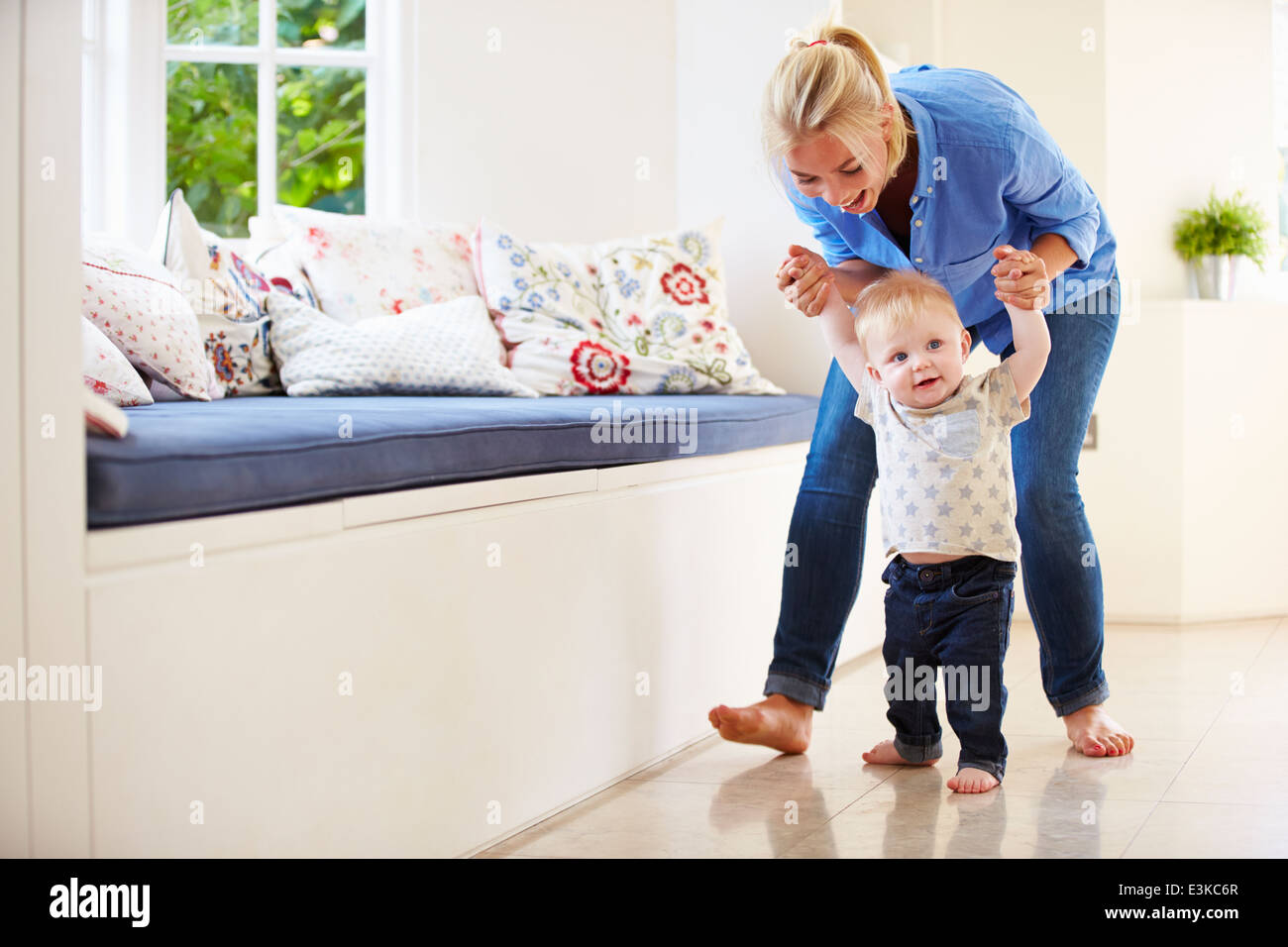 Mother Helping Young Son As He Learns To Walk Stock Photo
