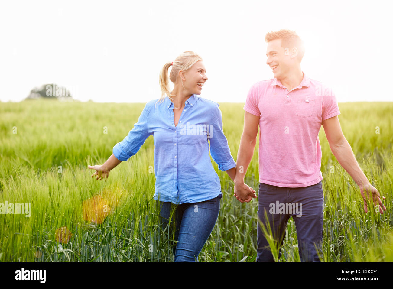 Romantic Couple Walking In Field Holding Hands Stock Photo - Alamy