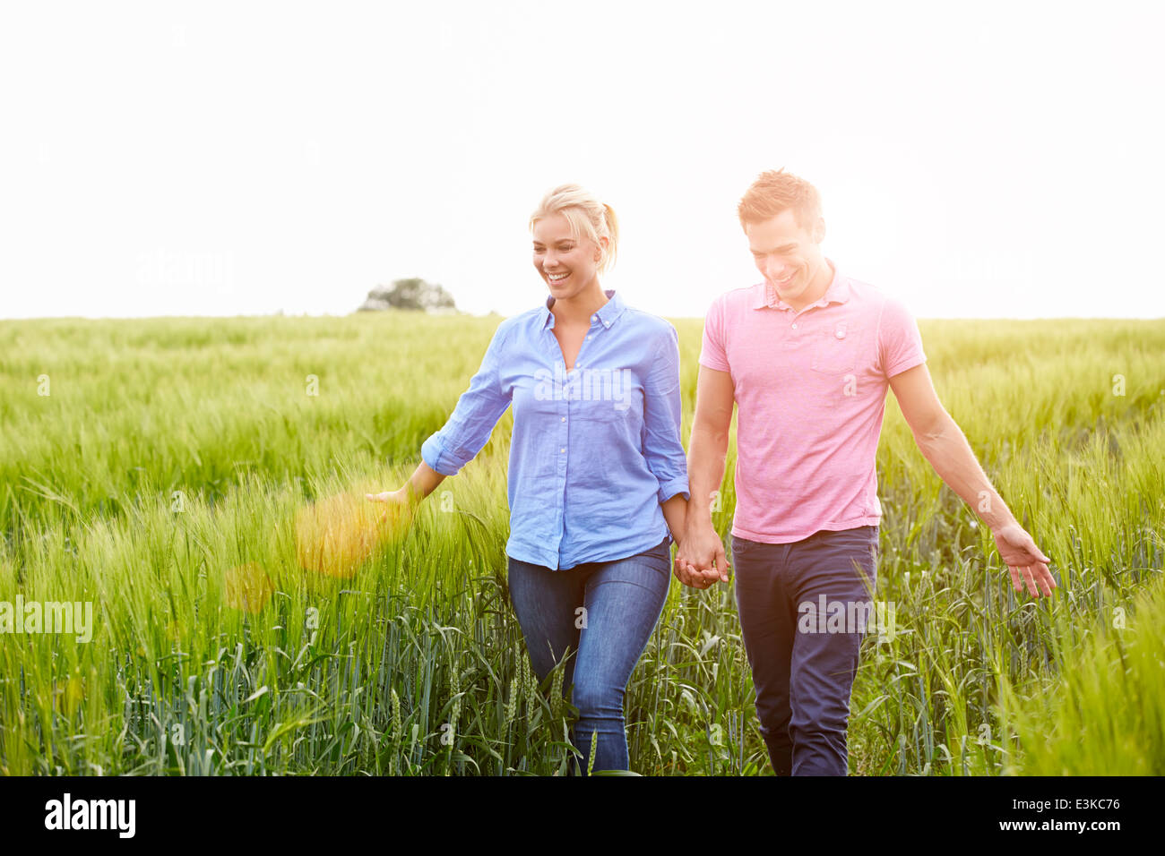 Romantic Couple Walking In Field Holding Hands Stock Photo - Alamy
