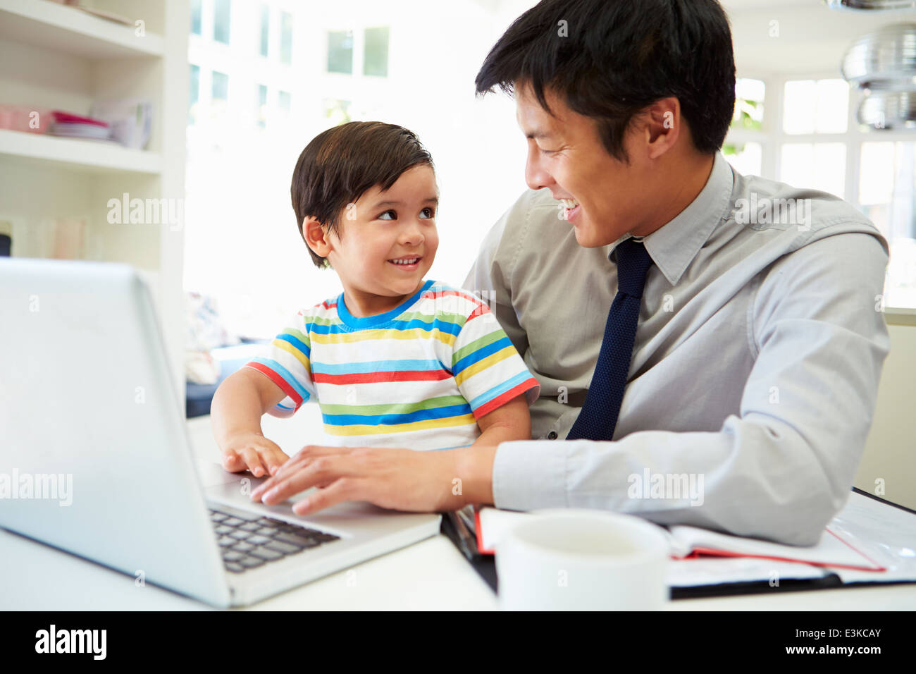 Busy Father Working From Home With Son Stock Photo