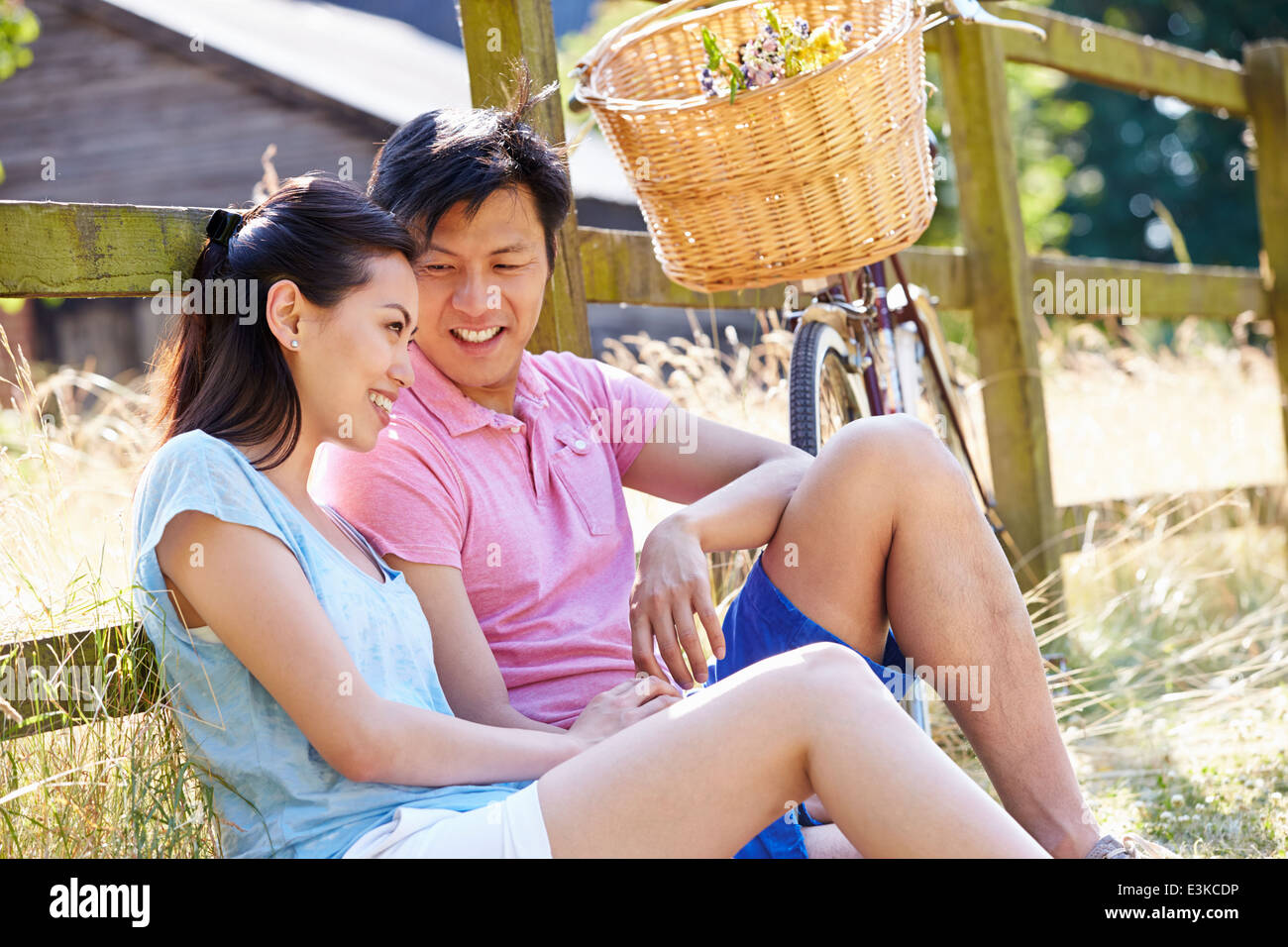 Asian Couple Resting By Fence With Old Fashioned Cycle Stock Photo