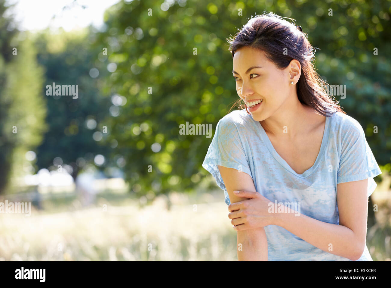 Pretty Asian Woman Sitting On Fence In Countryside Stock Photo