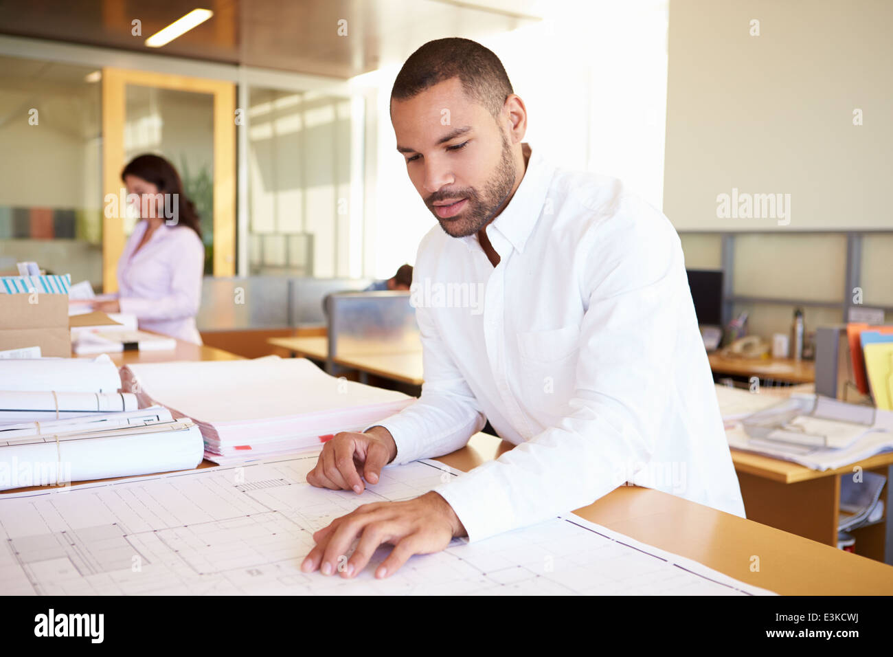 Male Architect Studying Plans In Office Stock Photo