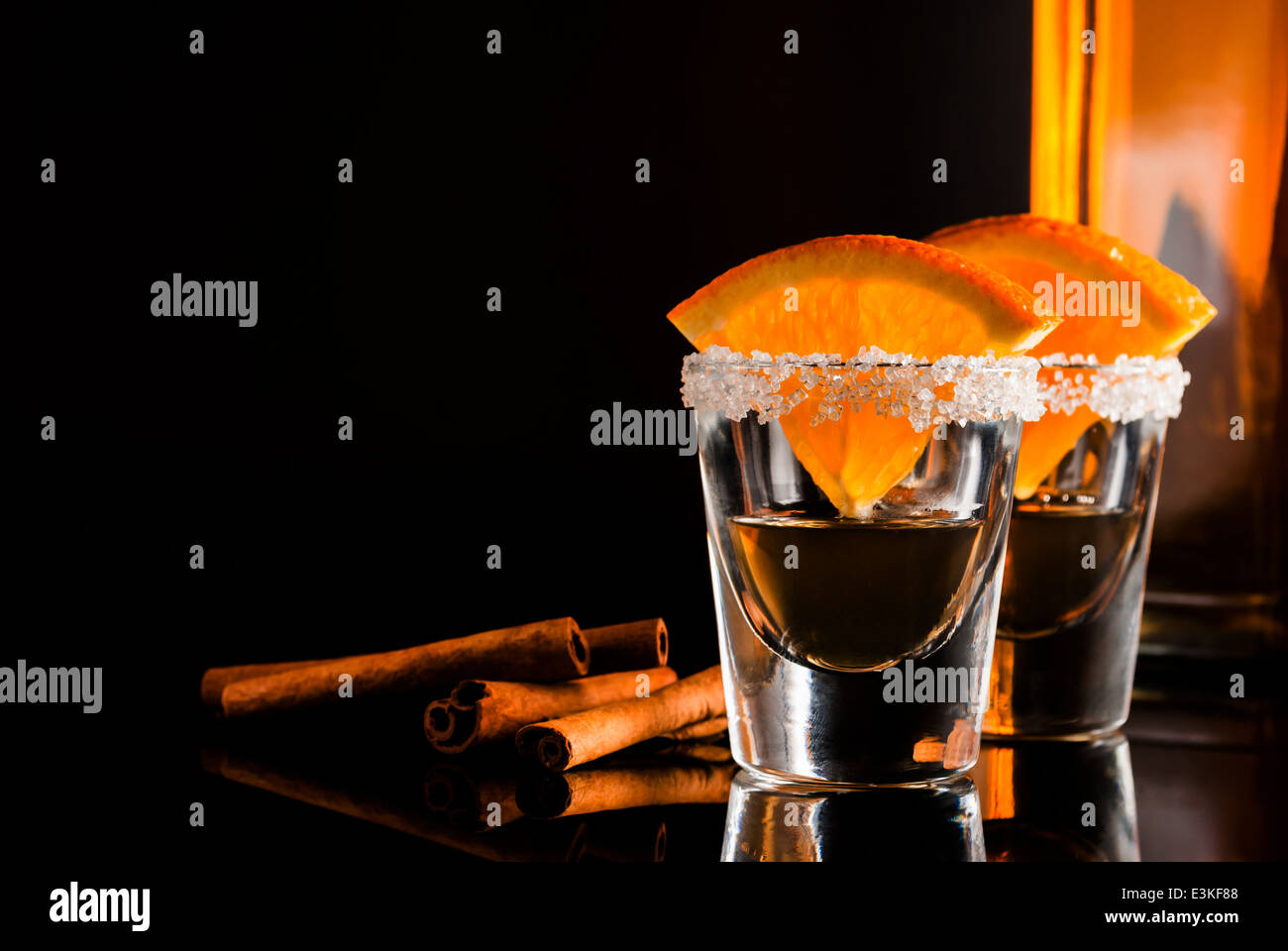 Gold tequila with orange and cinnamon on black reflect background Stock
