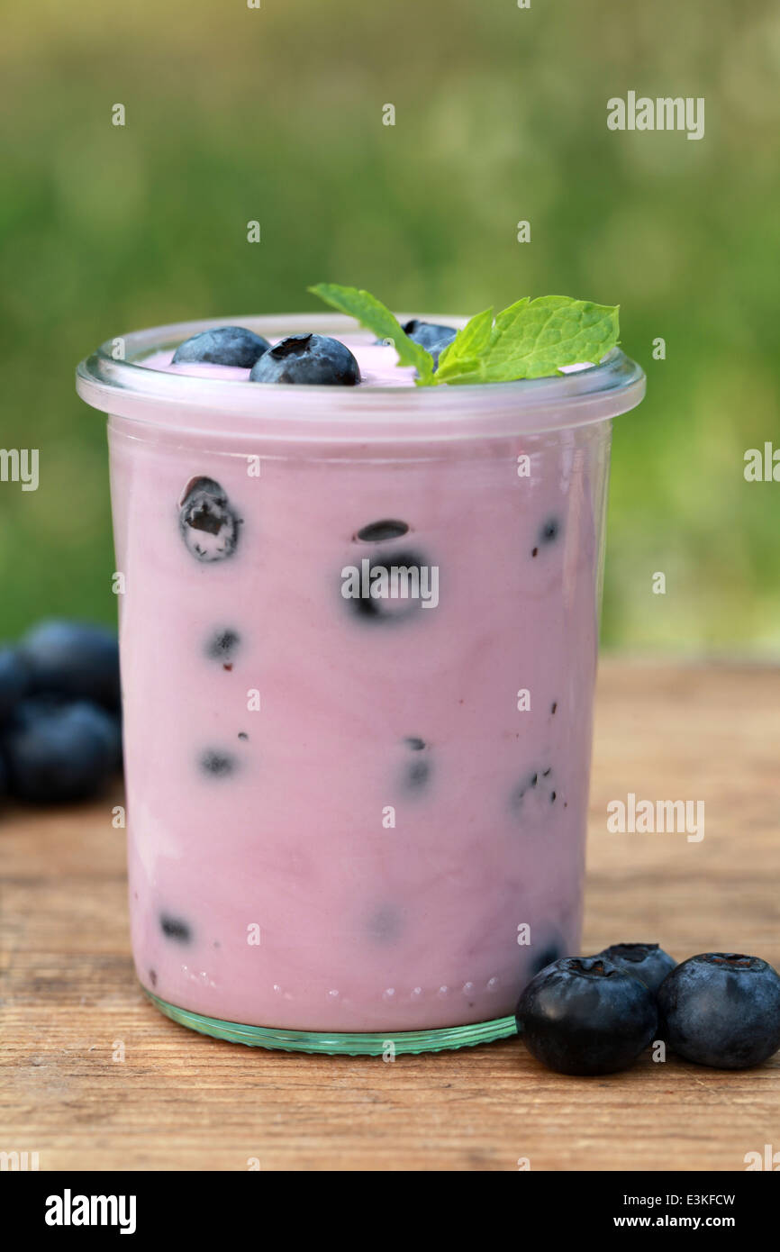 Blueberry yogurt in a jar on a wooden table served with fresh blueberries Stock Photo