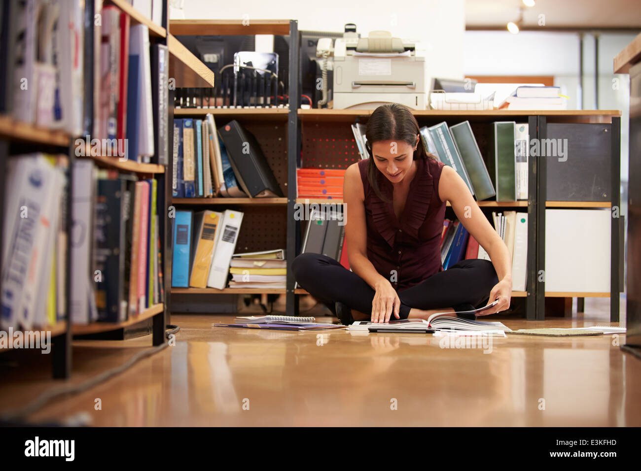 Businesswoman Sitting On Office Floor Reading Documents Stock Photo