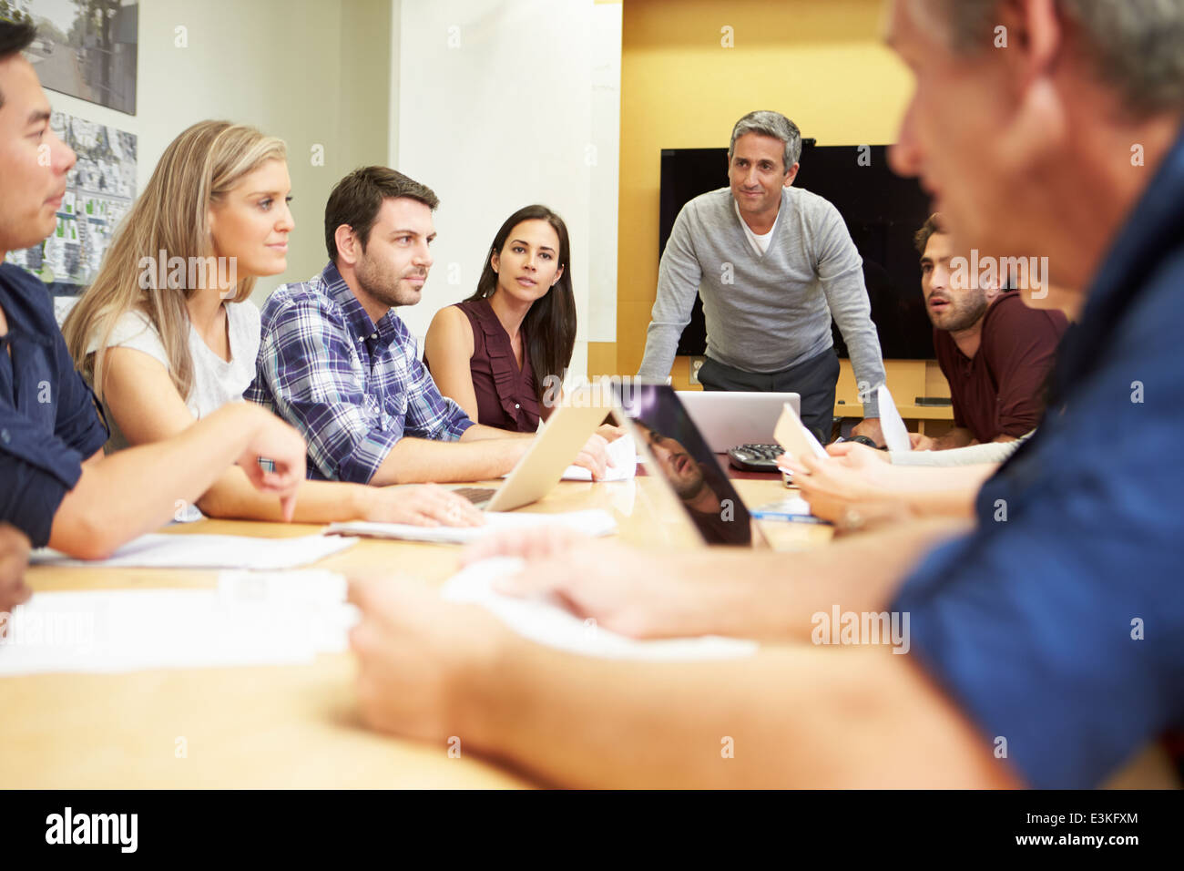 Male Boss Addressing Meeting Around Boardroom Table Stock Photo