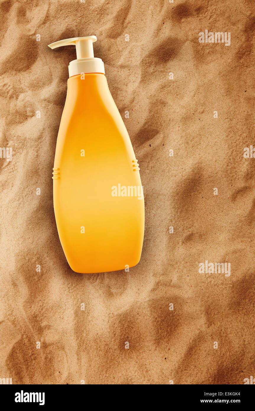 Bottle of sunbath oil or sunscreen on hot beach sand in summer. Stock Photo