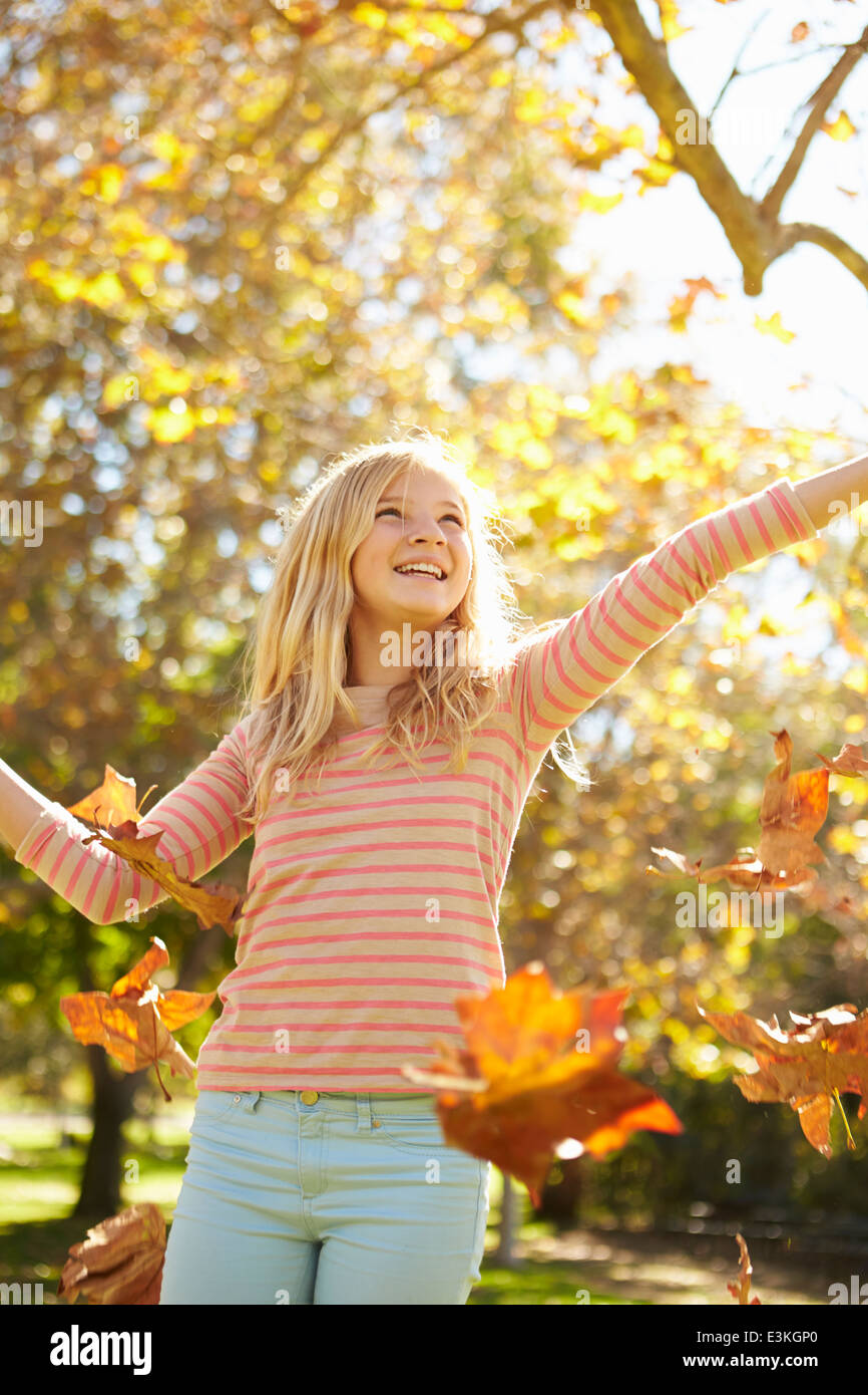 Young Girl Throwing Autumn Leaves In The Air Stock Photo