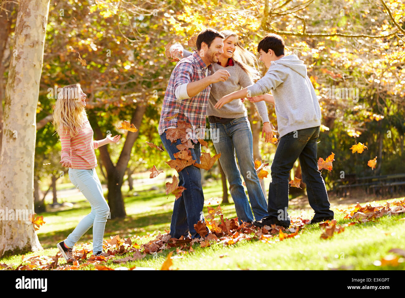 Family Throwing Autumn Leaves In The Air Stock Photo