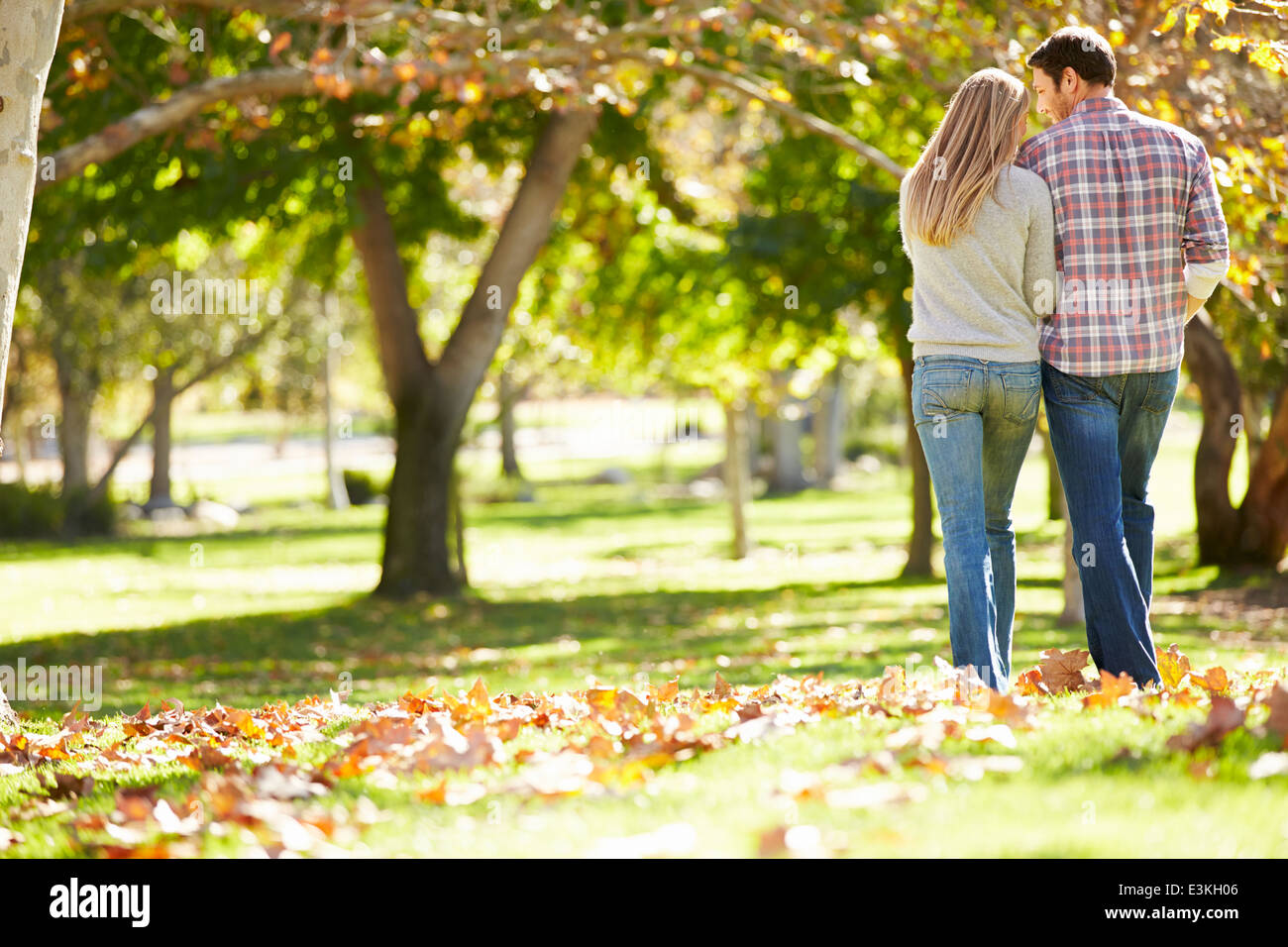 Rear View Of Romantic Couple Walking Through Autumn Woodland Stock Photo