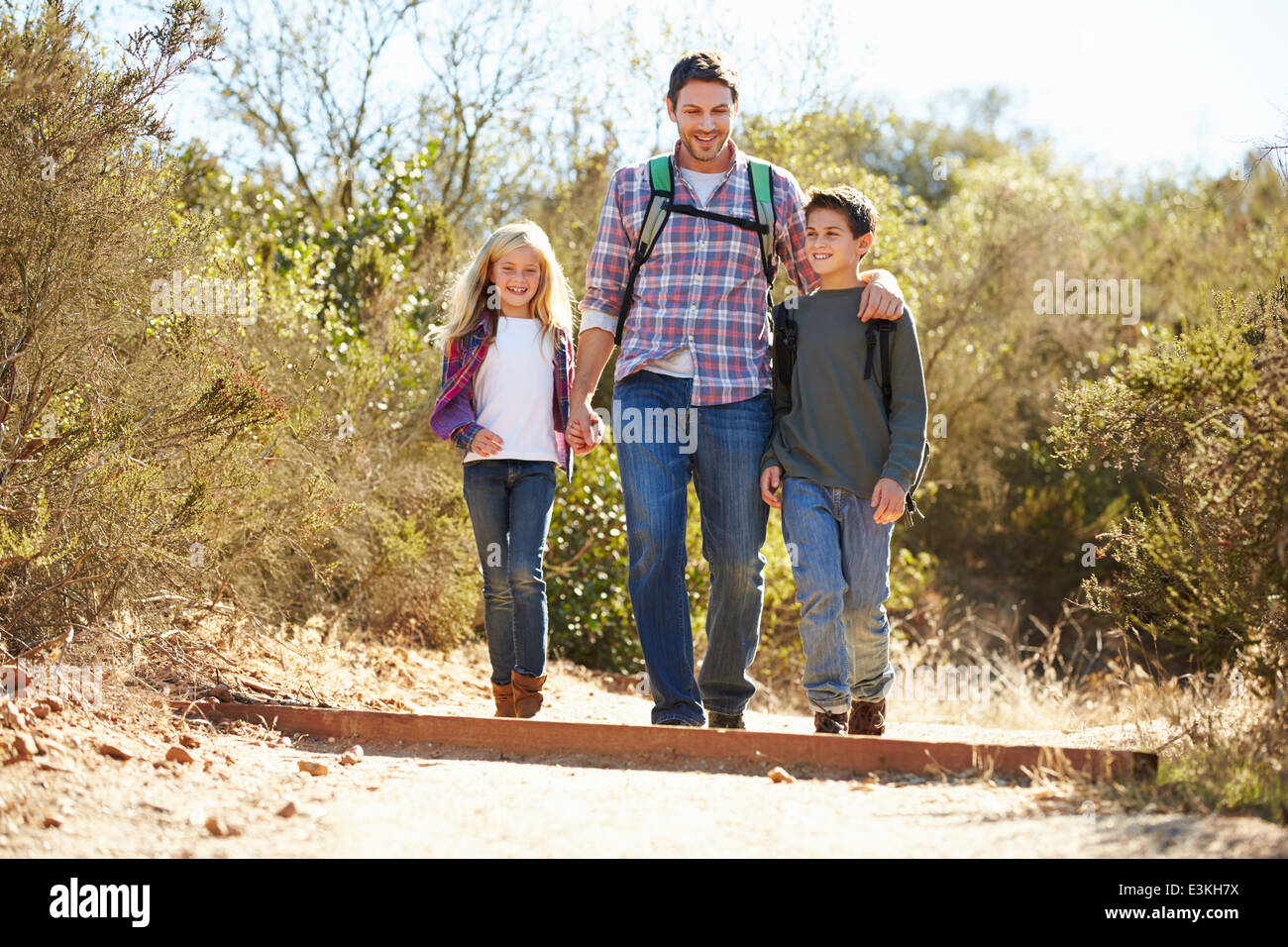 Father And Children Hiking In Countryside Wearing Backpacks Stock Photo