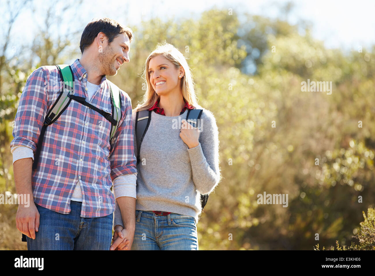 Couple Hiking In Countryside Wearing Backpacks Stock Photo