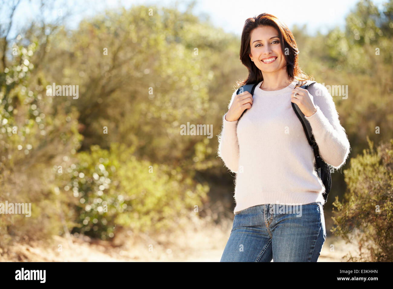 Portrait Of Woman Hiking In Countryside Wearing Backpack Stock Photo