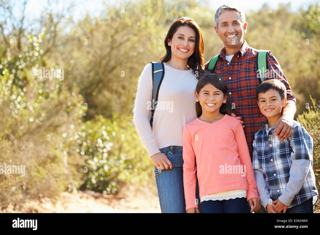 Portrait Of Family Hiking In Countryside Wearing Backpacks Stock Photo