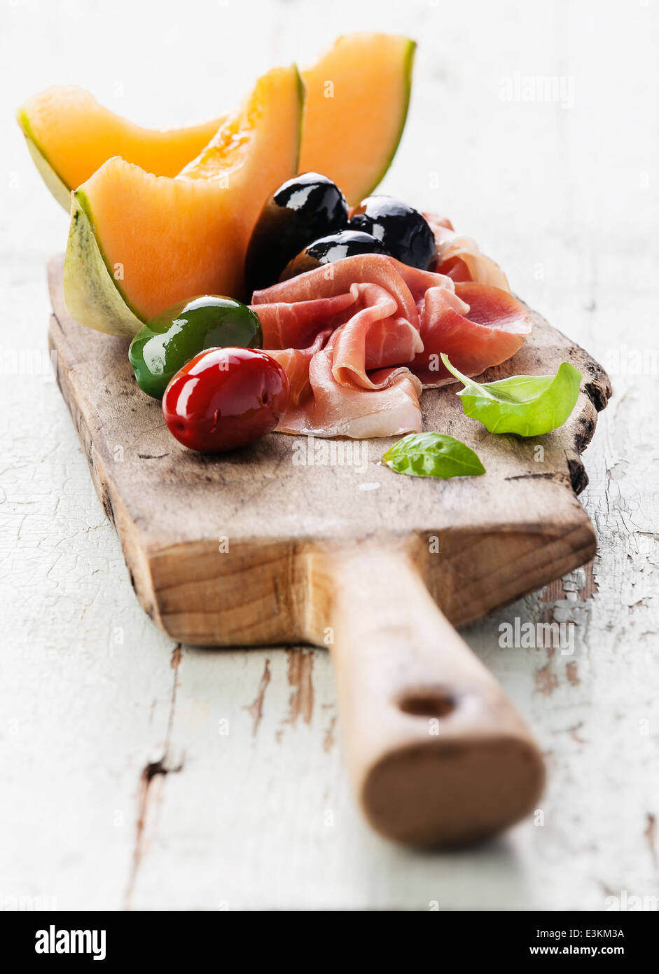 Prosciutto ham, Slices of melon cantaloupe and Olives on cutting board Stock Photo