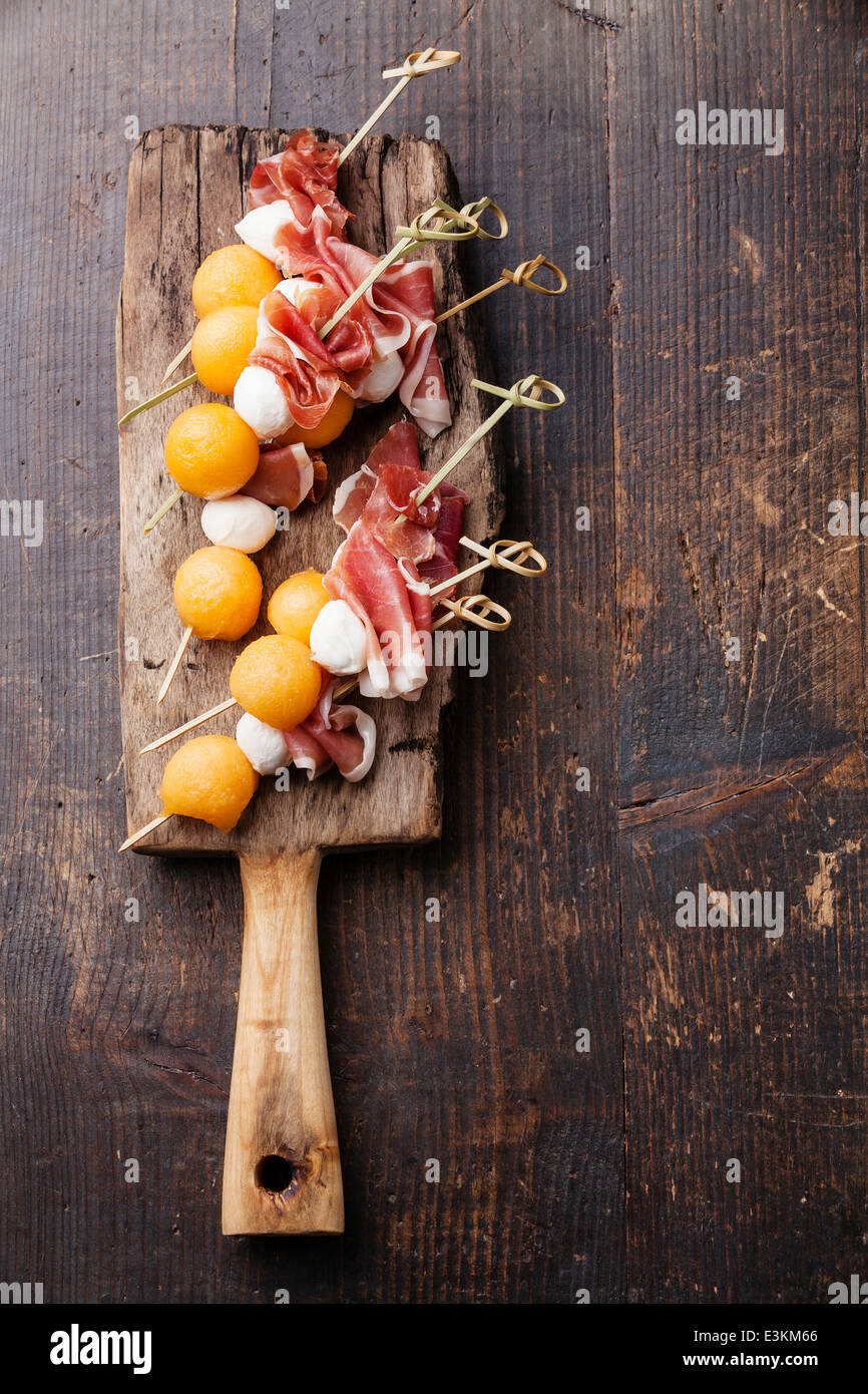 Mozzarella, prosciutto, melon canapes on textured background Stock Photo