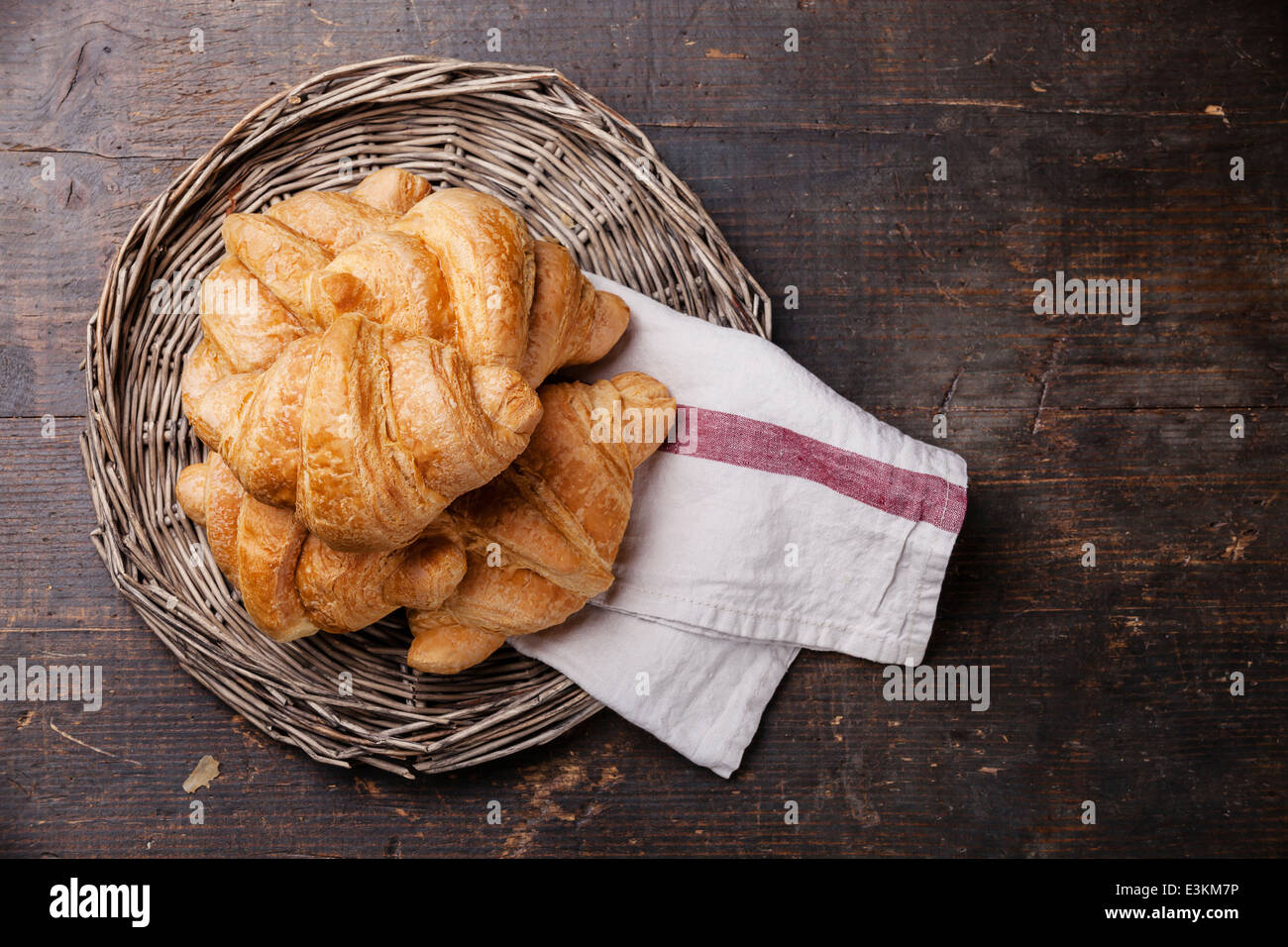Croissants in wicker tray on dark wooden background Stock Photo