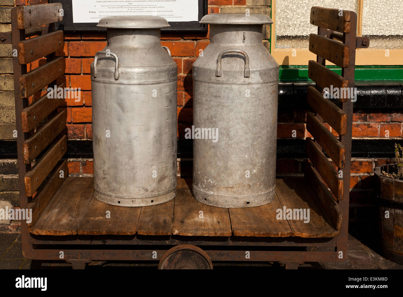 Two vintage milk churns on a railway trolley at a station Stock Photo