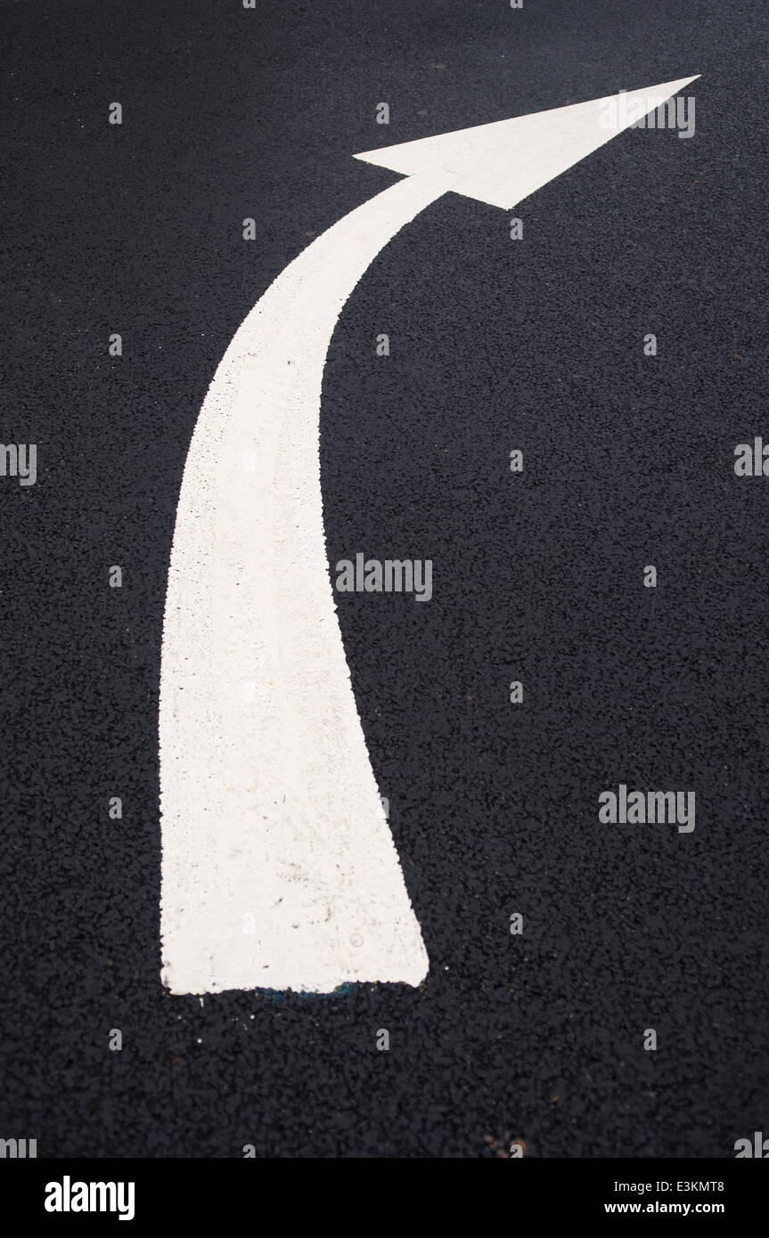 Curved white arrow painted on black tarmac. Stock Photo