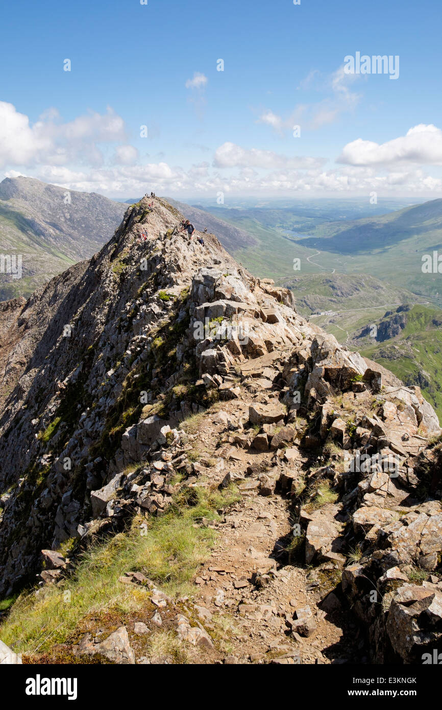 View back along red rocks on Crib Goch summit ridge top at start of Snowdon Horseshoe in mountains of Snowdonia North Wales UK Stock Photo