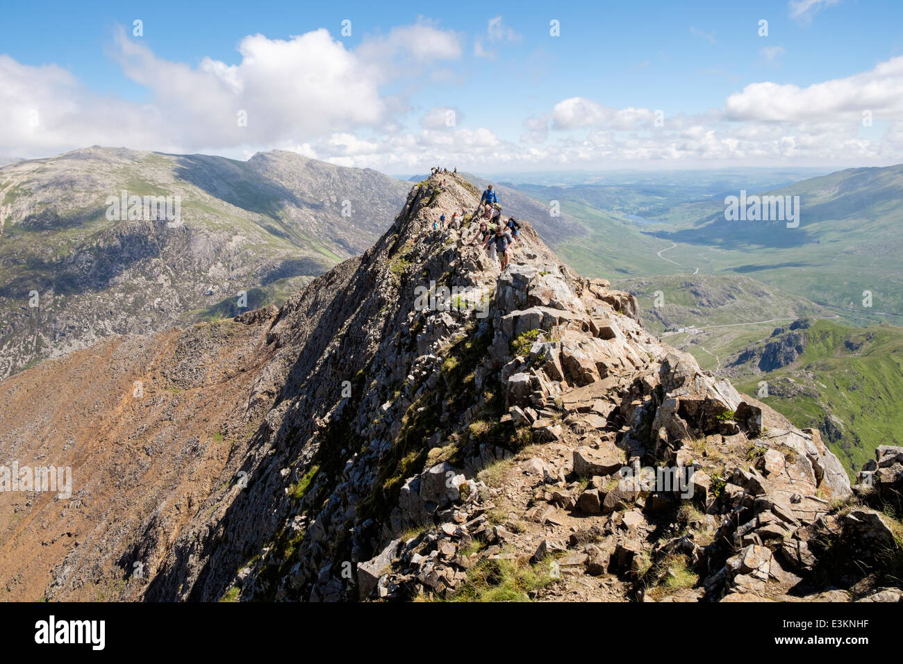 View back along red rocky Crib Goch ridge top scramble with hikers at start of Snowdon Horseshoe in mountains Snowdonia Wales UK Stock Photo