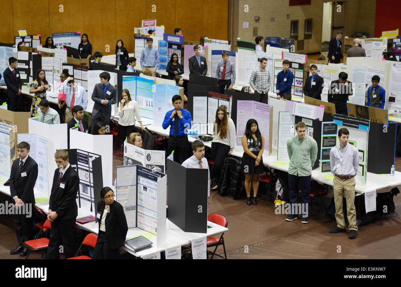 Science fair students waiting by their research posters to be judged Stock Photo