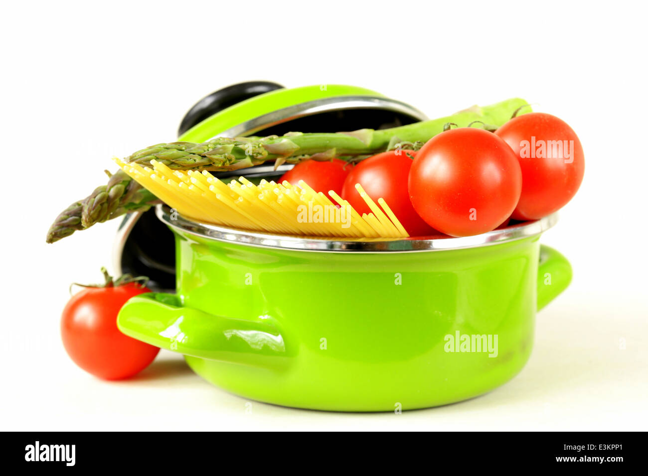 green pot full of vegetables (tomatoes, asparagus, mushrooms, broccoli) and pasta Stock Photo