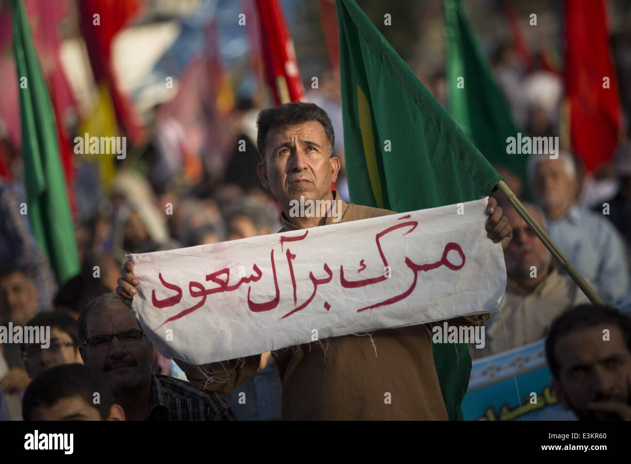Tehran, Iran. 24th June, 2014. June 24, 2014 - Tehran, Iran - An Iranian man holds a placard with a persian script that said, Down with AL-SAUD during a rally against the militant jihadist group, The Islamic State of Iraq and Syria (ISIS), in southern Tehran. Morteza Nikoubazl/ZUMAPRESS Credit:  Morteza Nikoubazl/ZUMA Wire/ZUMAPRESS.com/Alamy Live News Stock Photo