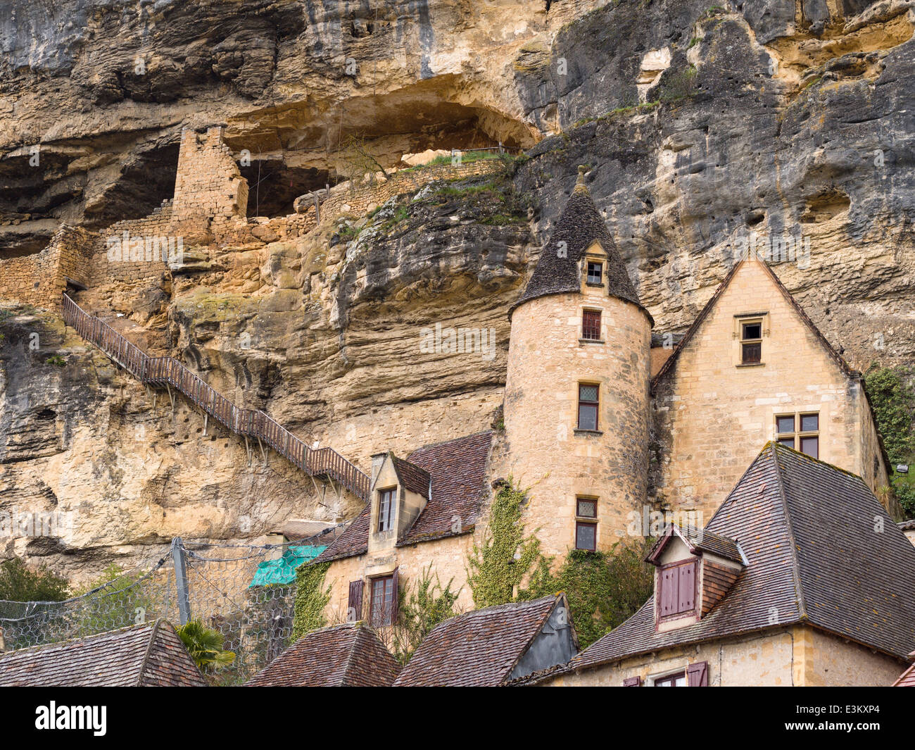 Caves above the fine houses of the lower village of La Roche. A rickety old wooden stair connects the towered houses to caves Stock Photo