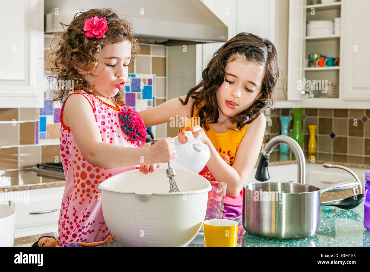 Two girls (4-5, 8-9) cooking together Stock Photo