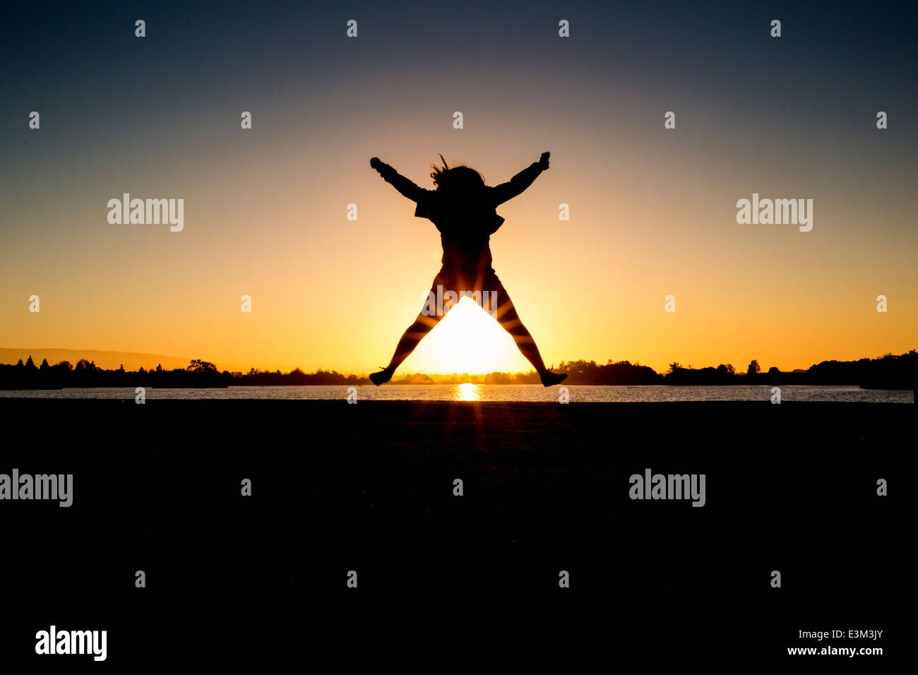 Silhouette of teenage girl (13-15) jumping Stock Photo
