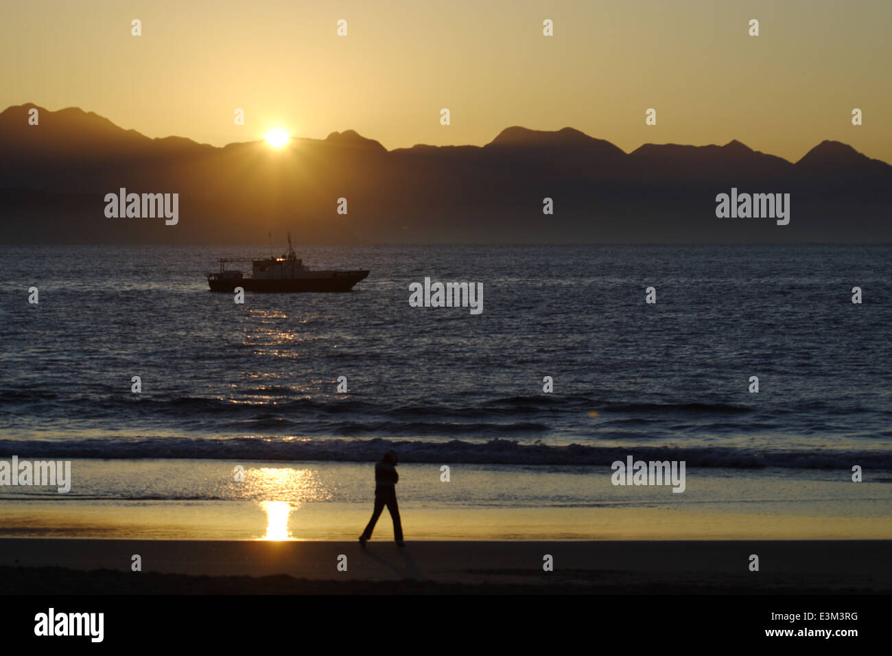 Silhouette of child playing on Diaz beach at sunrise, Mossel Bay, South Africa Stock Photo