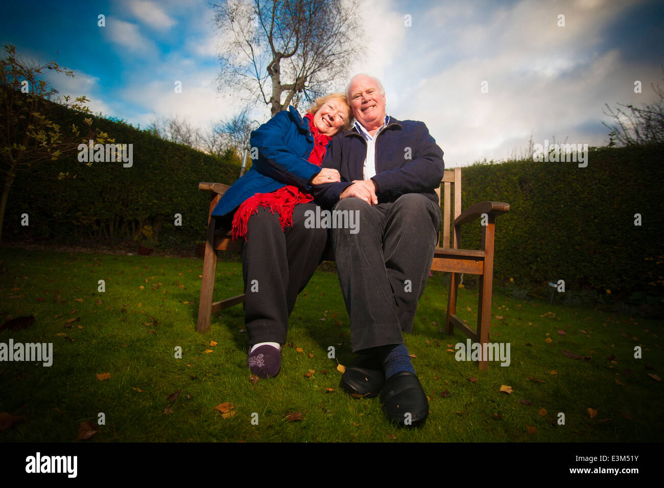A retired couple, relaxing on a bench in a garden. Stock Photo